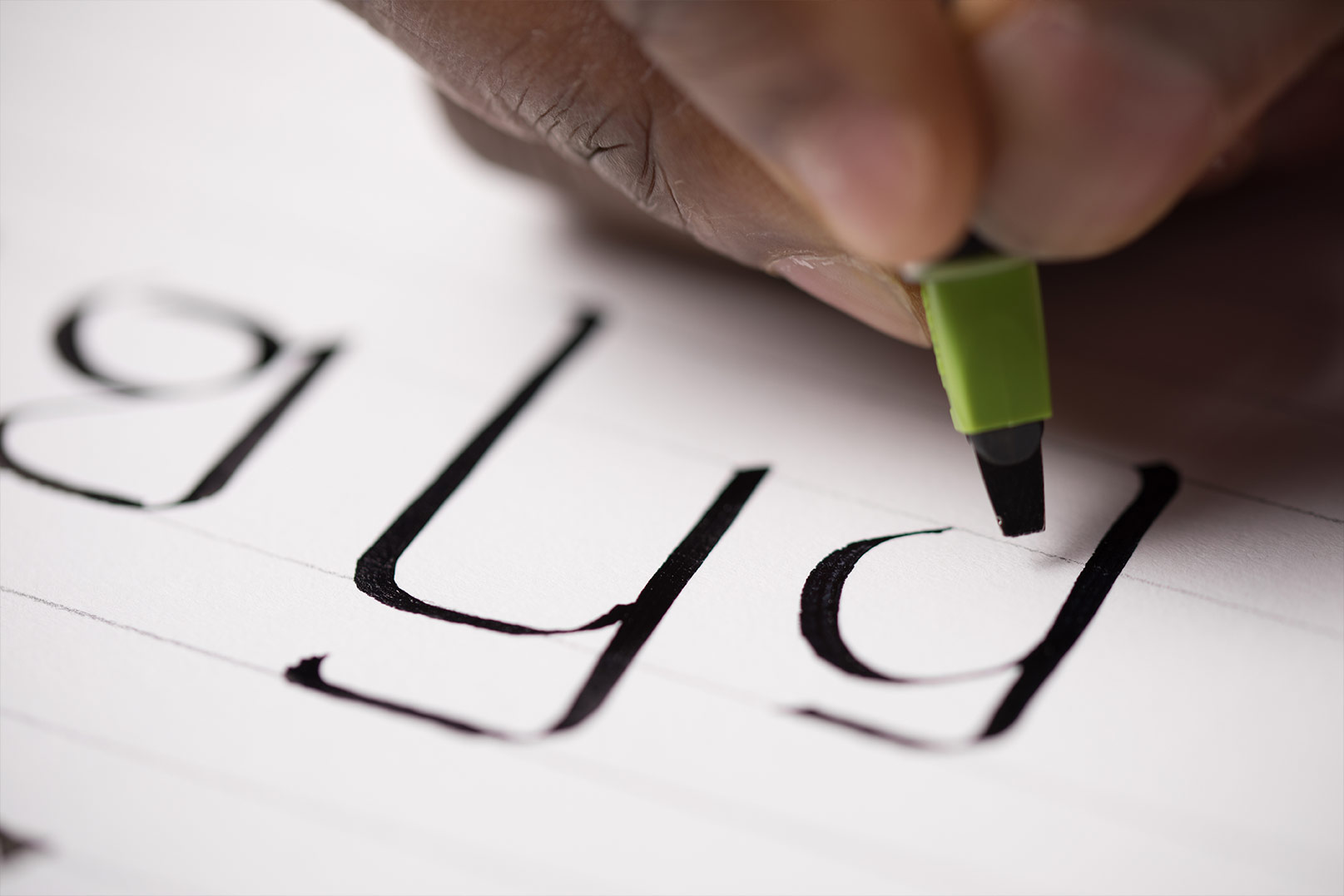 Close-up photograph of a hand writing letters in the ADLaM alphabet with a felt-tip pen