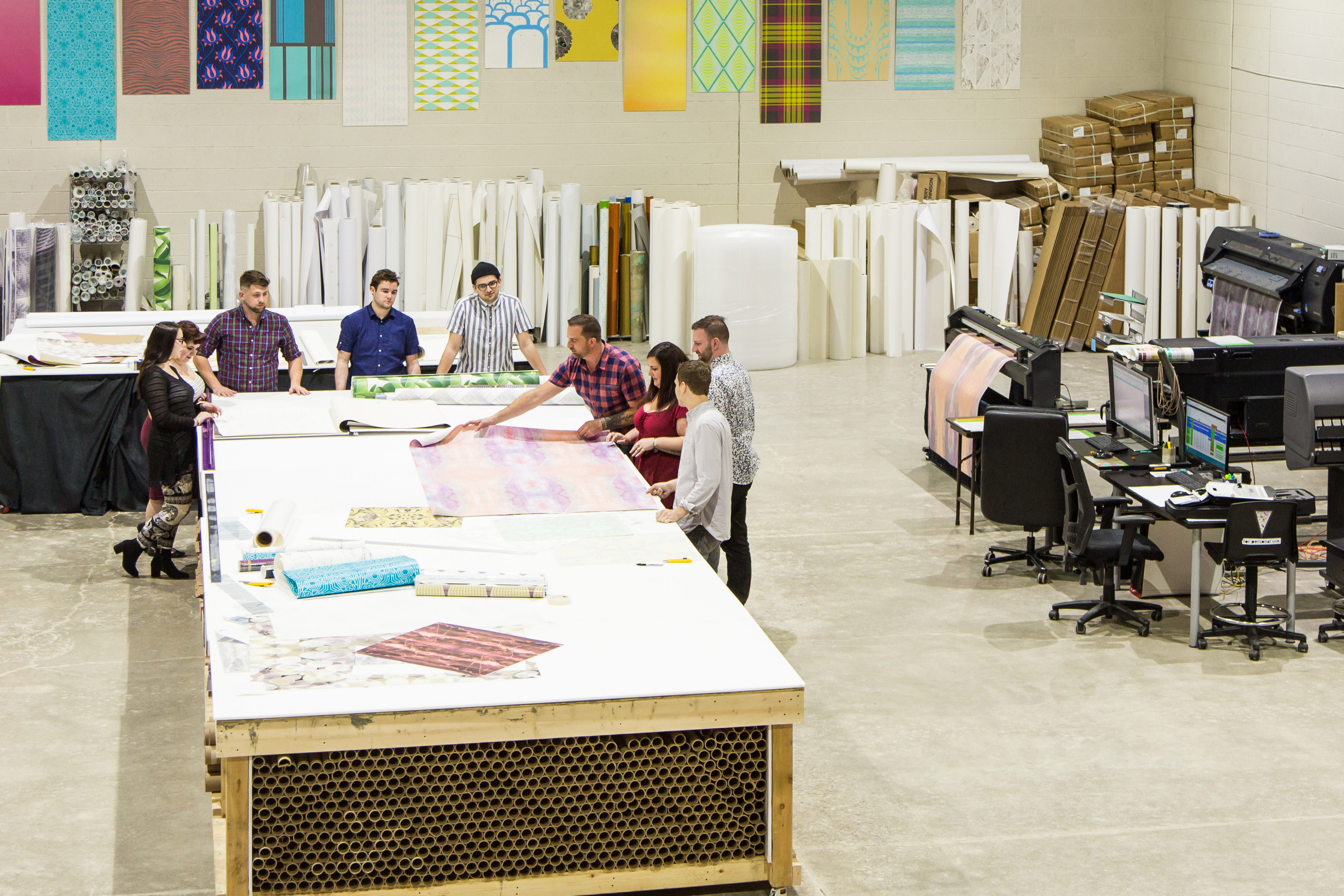 Photo taken from above showing employees standing around a table.