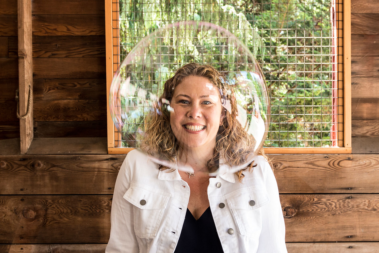 A portrait of Katie with her daughter's bubble floating in front of her