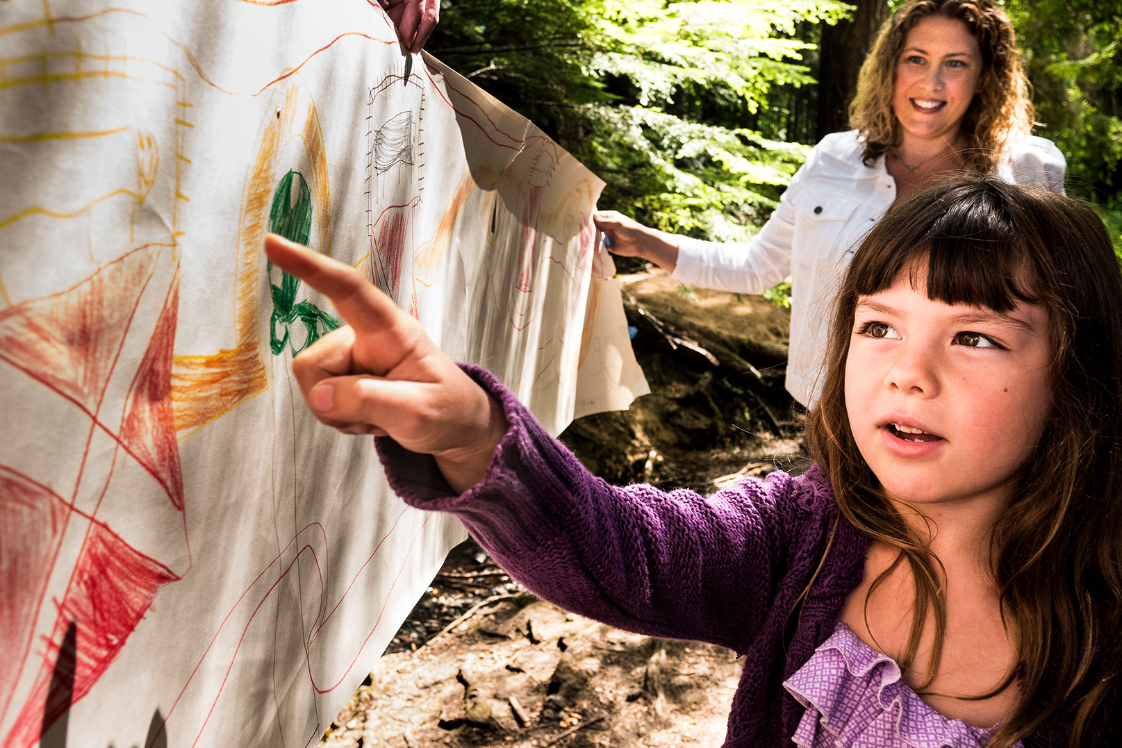 Katie's daughter pointing at her drawing on a banner