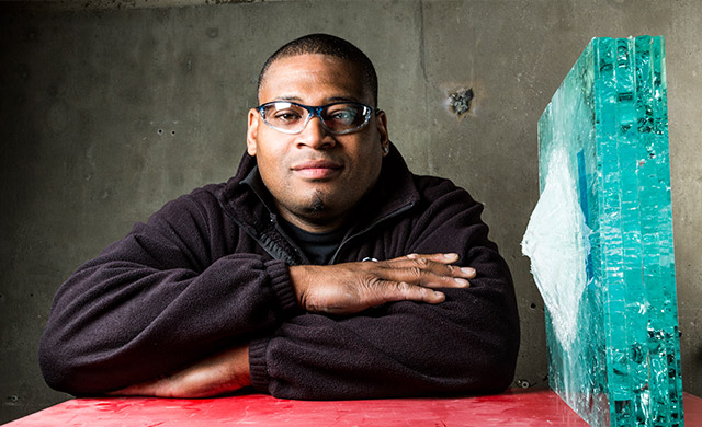 Derek sitting next to a piece of bullet tested glass