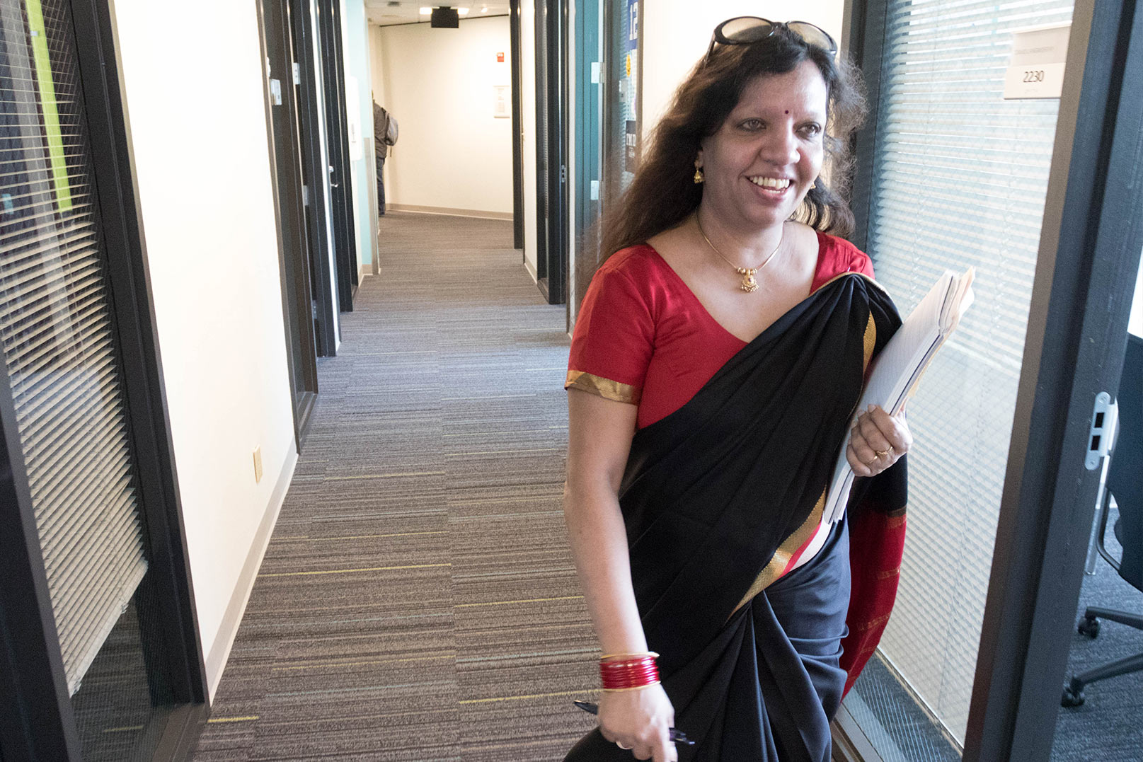 Kousy in her sari smiling and walking down the hall
